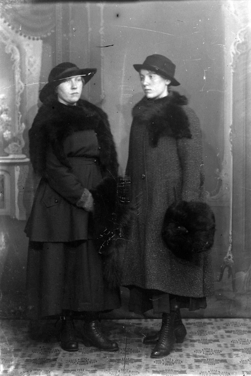 Studioportrett av to vinterkledd kvinner.