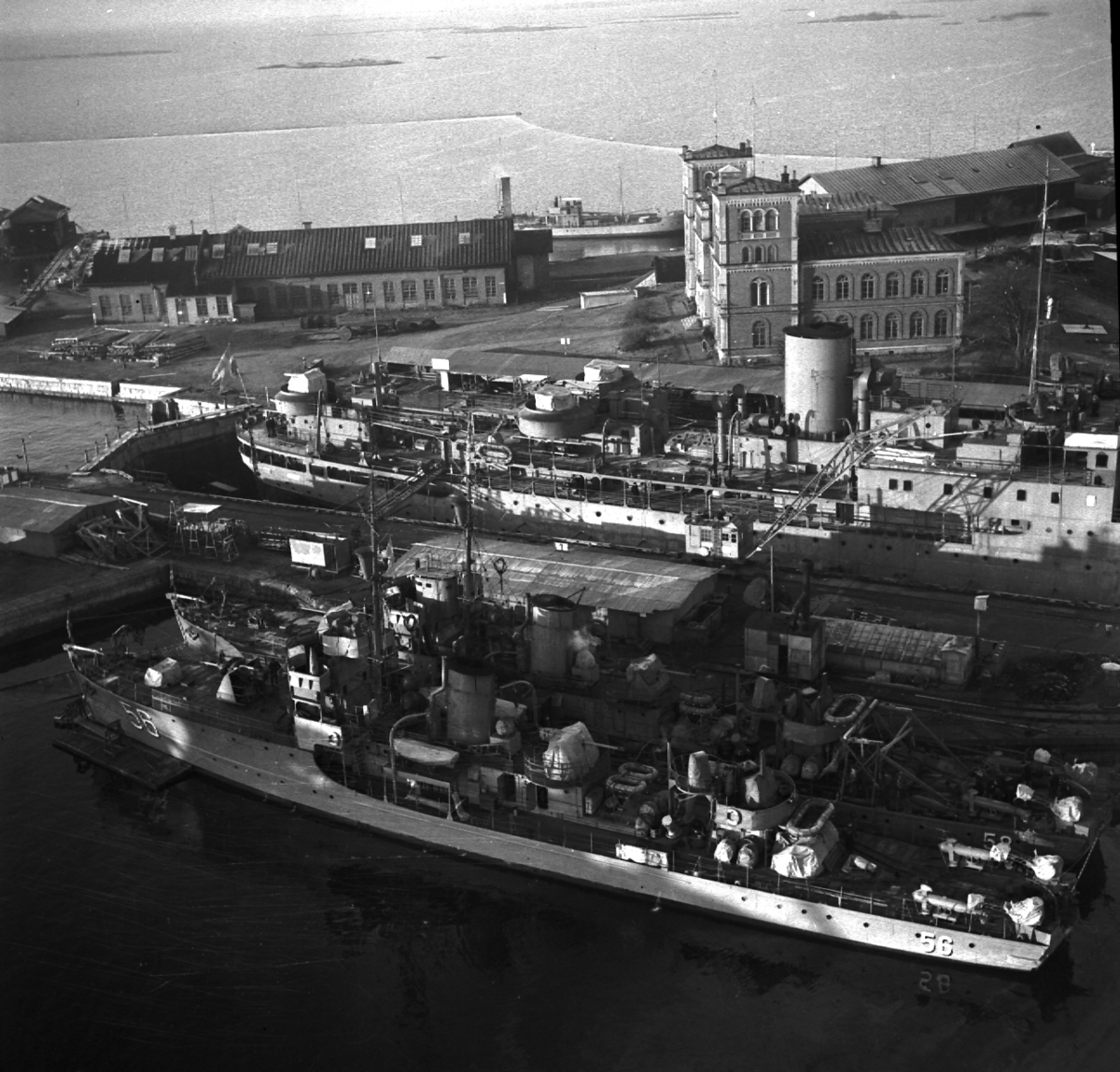 Röd tegelbyggnad i två till fyra våningar med två torn på varje sida.