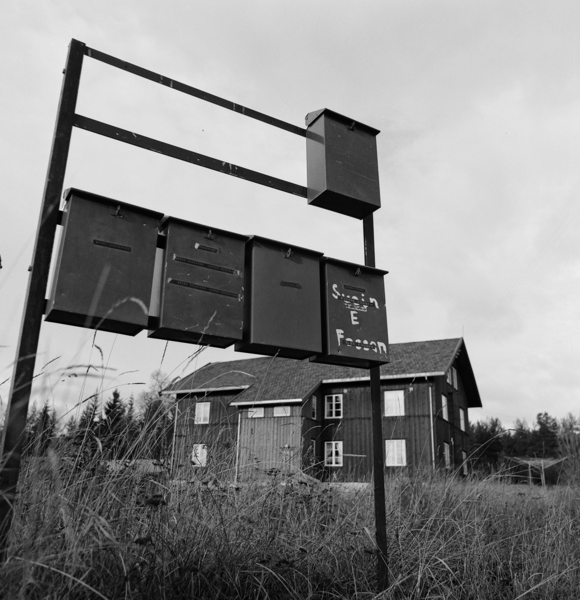 Postkassestativ. Øvre Tregård, arbeiderbolig for Aadals Brug, fra midten av 1880 årene. Ådalsbruk. Se Lautin 1978 s. 150. Artikkel Av Geir Hovensjø. "Det var en gang et industrisamfunn" Løten.  Brant ned lørdag 20. oktober 1979.