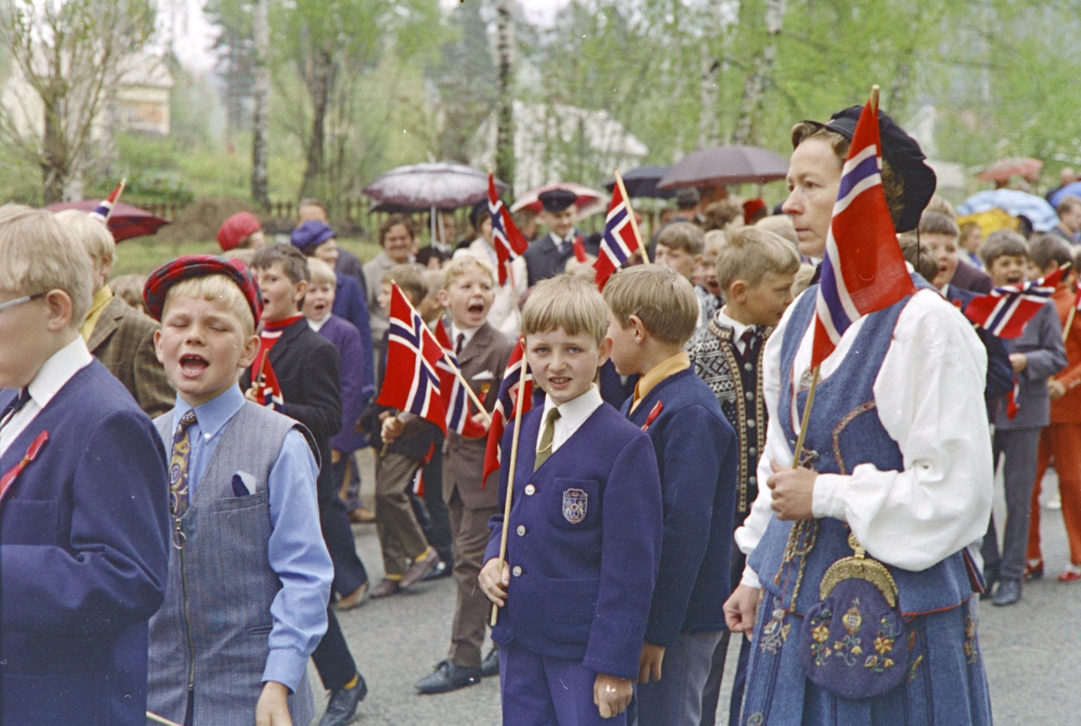 Brumunddal, 17.mai. 
Barnetoget. Mørkved skole.
Nasjonaldag. Barn, Mørkved skole. Lærer Kirsten Jovall, f. Nyhus. Fra venstre rød caps Ole Erik Dammen, så Stein Korsveien i brun dress, ...Hovland, gutt i strikkejakke må være Sigvart Jovall. Bak Kirsten skimtes Tormod Høisveen og Kjell Rune Hagelund.