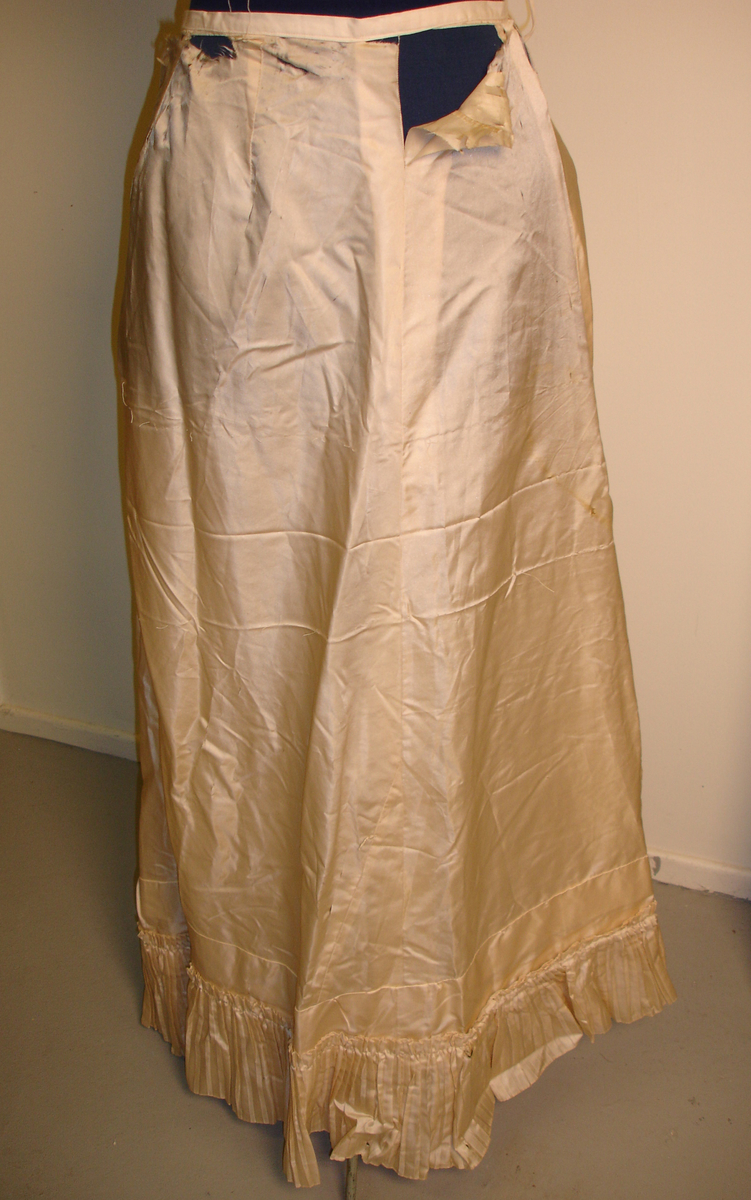 Tilhører brudekjolen kmk 5523
underskjørt, silkeunderskjørt med plissert kappe nederst. Er noen revner i stoffet
