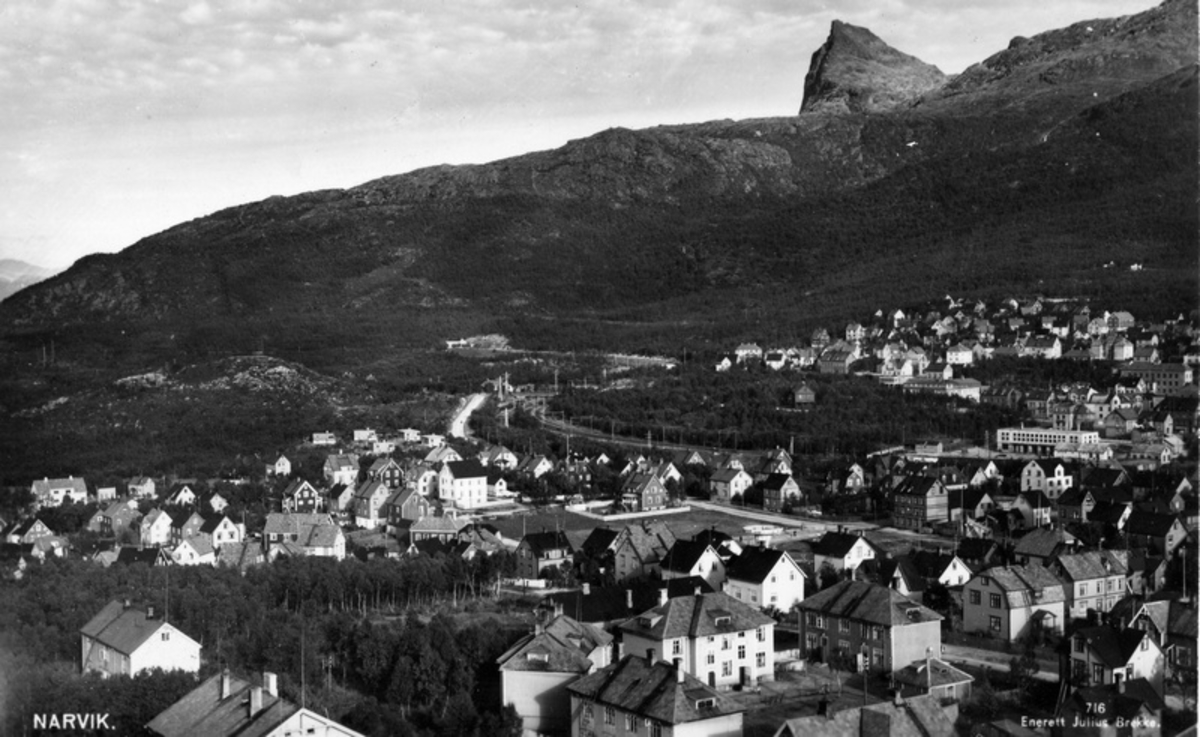 Kommunegårdene på Frydenlund.  Kommunegård 6 til venstre i bildets forkant. Kommunegårdene var en samling gårder med flere leiligheter. Eid av Narvik Kommune. Bildet må være tatt etter 1937-39 fordi funkishusene i Finnbekken er oppført, men før 1941 fordi ingen brakker er oppført på Rønningtomta. Fra v.: Brugata 13 (Skråstilt), Brugata 11, Brugata 9. Taket i bildets venstre hjørne er av Jernbanens bolig kaldt Gamle Sykhuset.