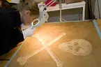 Konservator från Armémuseum tittar till en inlånad piratflagga från Ålands Sjöfartsmuseum.