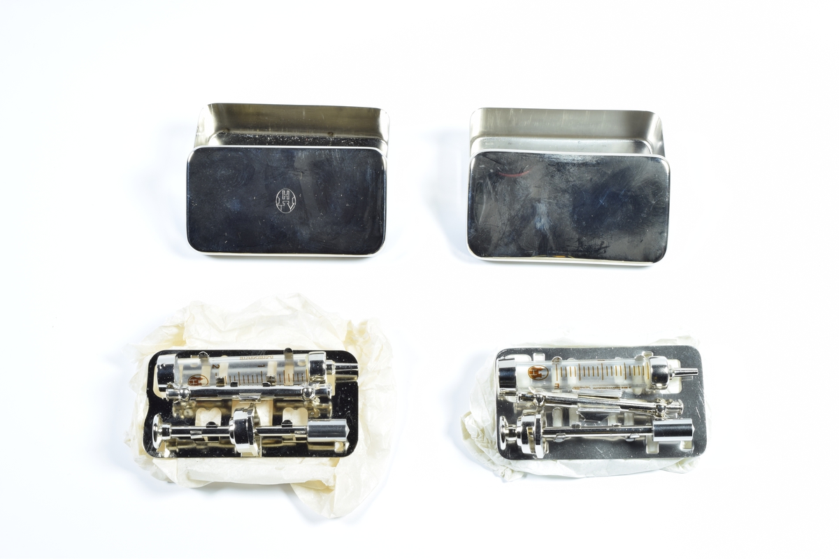 Skrin med lokk i hvit porselen. Skrinet inneholder diverse gjenstander brukt i apotekvirksomhet.

Skrinnet inneholder:

1 grønn eske med "Sterilpakning for kanyler". I esken ligger det 13 små rør i glass og 1 i plast.

1 hvit eske med 8 ampuller med Dolormin til injeksjon.

2 uåpnede pakker med sprøyter, produsert i Tyskland. Eskene er dekorert med et blått kors på en gullfarget bakgrunn og en logo som viser et hus og bostaven H.

2 kvadratiske metallbokser med sprøyter. På lokket til en av boksene er det en logo som viser et hus og bokstaven H.

1 pose med seks munnstykker til nesespylere.

1 lite knivblad med tager og bokstavene A L.

1 pose med flere små stålrør med et lite dråpeformet "håndtak" i en ende.

1 liten pumpe i rød gummi.