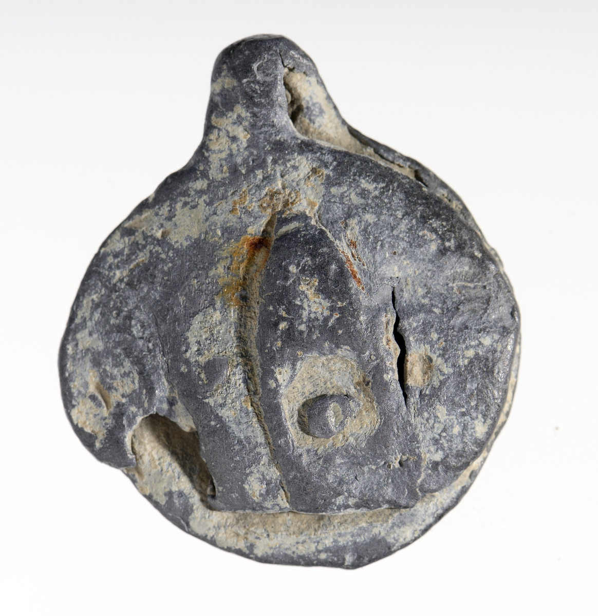 Vareplombe med begge plaketter, nagle og streng bevart. Gjenstanden er nedslitt men viser svake tegn til preg på begge plaketter. Preget er utydet. 