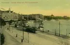 Stockholm, vy över Södra Blasieholmshamnen från norr med Grand Hotel och Nationalmuseum i bakgrunden. Kolorerat vykort, färglitografi.