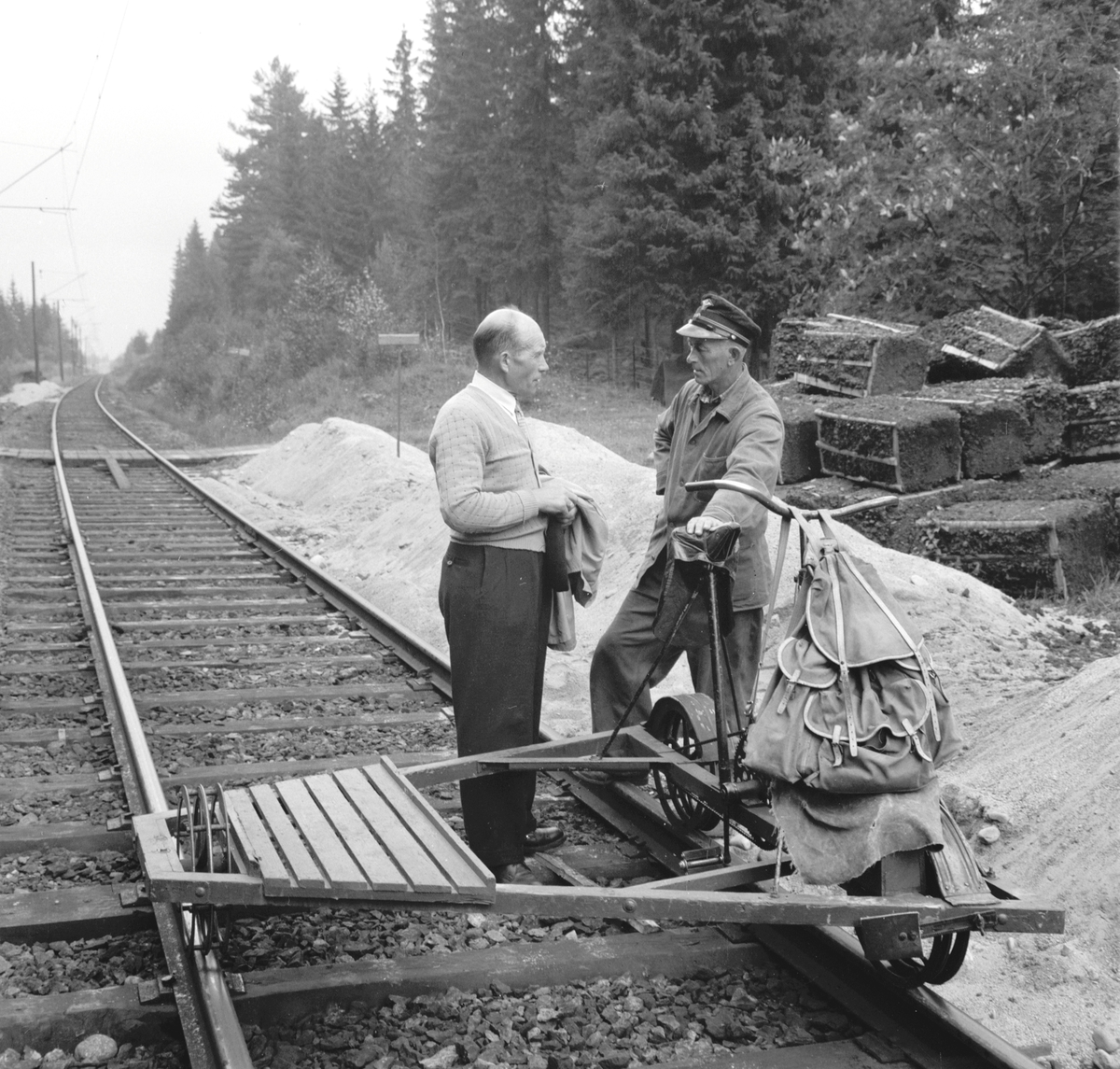 Tangen, NSB, utskifting av jernbaneskinner, den gamle skinnegangen som ble lagt en gang på 1920 tallet med 12 meters lange skinner, ble nå skiftet ut med nye skinner på 15 til 45 meters lengder. For å unngå telehiv ble gammel vannholdig jordmasse skiftet ut med spesialpressede torvballer og gamle sviller og slagg som skal isolere de underliggende jordmassene, oppå dette blir det lagt, sand, grus og pukk og nye sviller.  
Utskiftingen av jordmassene og legging av nye jernbaneskinner startet våren 1958 nord for Espa stasjon og i midten av oktober regnet de med å nå Stange stasjon. distriktsjef Lorentz H. Aas i samtale med arbeider, en dressin, i bakgrunnen torvballer som ble brukt som isolasjon,