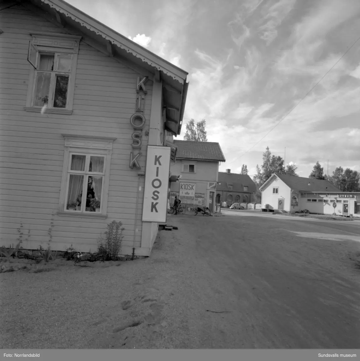 Skyltning utefter vägen mellan Sundsvall och hälsingegränsen 1961. Bland annat Bergafjärden, Dingersjö, Bredsand och Kusten. I Njurundabommen fick länge trafikanterna söderifrån lätta på gasen och anamma ett makligare tempo. Men innan vägen som nu blivit ”gamla E4:an” byggdes, var det så här som korsningen i Bommen såg ut. Längst till höger i bild skymtar det före detta bankhuset som fortfarande finns kvar.