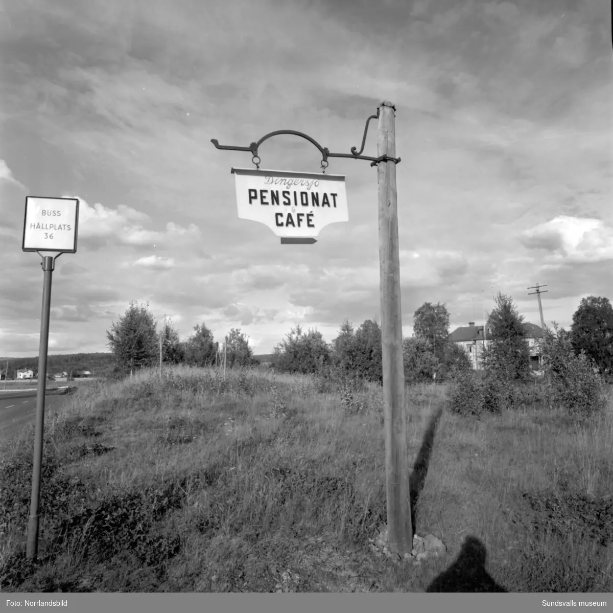 Skyltning utefter vägen mellan Sundsvall och hälsingegränsen 1961. Bland annat Bergafjärden, Dingersjö, Bredsand och Kusten. I Njurundabommen fick länge trafikanterna söderifrån lätta på gasen och anamma ett makligare tempo. Men innan vägen som nu blivit ”gamla E4:an” byggdes, var det så här som korsningen i Bommen såg ut. Längst till höger i bild skymtar det före detta bankhuset som fortfarande finns kvar.