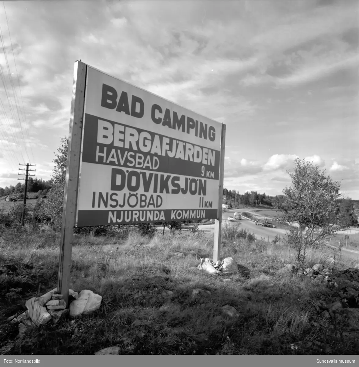 Skyltning utefter vägen mellan Sundsvall och hälsingegränsen 1961. Bland annat Bergafjärden, Dingersjö, Bredsand och Kusten. I Njurundabommen fick länge trafikanterna söderifrån lätta på gasen och anamma ett makligare tempo. Men innan vägen som nu blivit ”gamla E4:an” byggdes, var det så här som korsningen i Bommen såg ut. Längst till höger i bild skymtar det före detta bankhuset som fortfarande finns kvar.