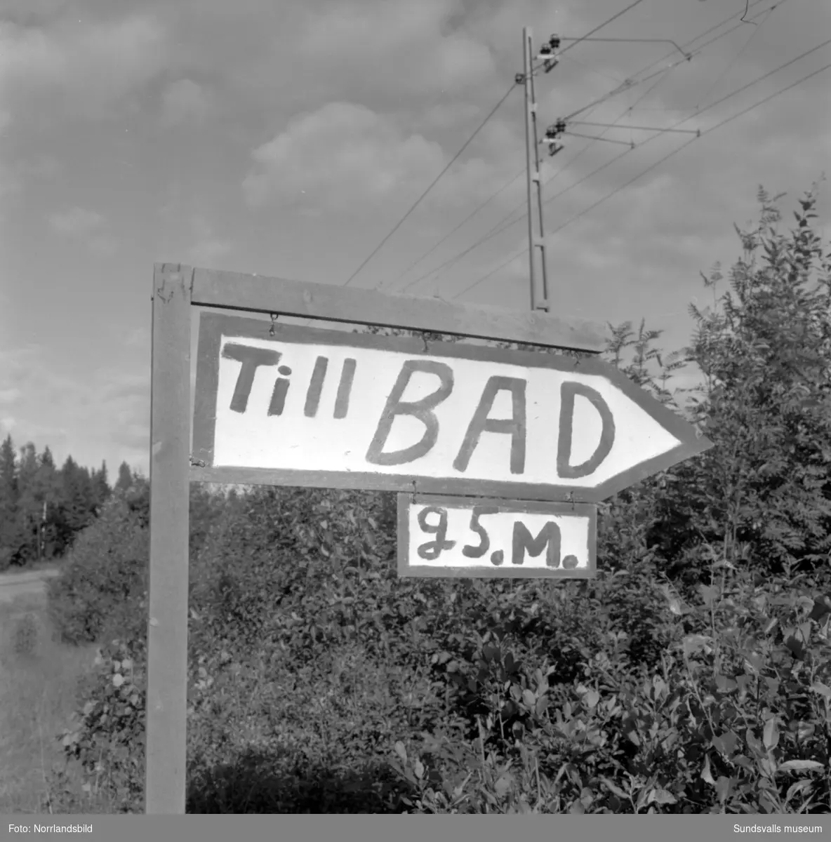 Skyltning utefter vägen mellan Sundsvall och hälsingegränsen 1961. Bland annat Bergafjärden, Dingersjö, Bredsand och Kusten. I Njurundabommen fick länge trafikanterna söderifrån lätta på gasen och anamma ett makligare tempo. Men innan vägen som nu blivit ”gamla E4:an” byggdes, var det så här som korsningen i Bommen såg ut. Längst till höger i bild skymtar det före detta bankhuset som fortfarande finns kvar.