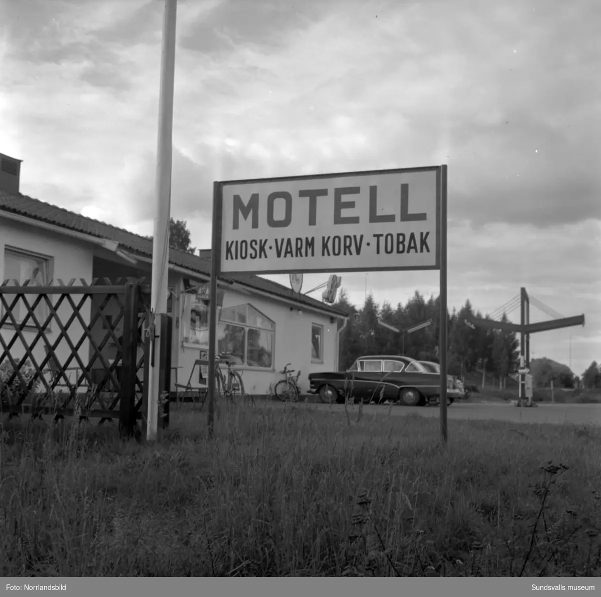 Skyltning utefter vägen mellan Sundsvall och hälsingegränsen 1961. Bland annat Bergafjärden, Dingersjö, Bredsand och Kusten. I Njurundabommen fick länge trafikanterna söderifrån lätta på gasen och anamma ett makligare tempo. Men innan vägen som nu blivit ”gamla E4:an” byggdes, var det så här som korsningen i Bommen såg ut. Längst till höger i bild skymtar det före detta bankhuset som fortfarande finns kvar.