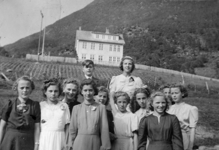 Konfirmanter foran Sigerfjord skole i Sortland. Skolen blei bygd i 1917. Foran fra venstre: Olaug Bendiksen, Oddrun Bendiksen, Gerd Strand, Regine Pedersen, Borghild Isaksen, Hilbjørg Akselsen (Haugstvedt), Brynhild Akselsen (Haugstvedt), Solveig Olsen, Synnøve Meland og Aud Bendiksen. Bak står Knut Erik Ramberg og Ruth Marie "Mosse" Olsen.