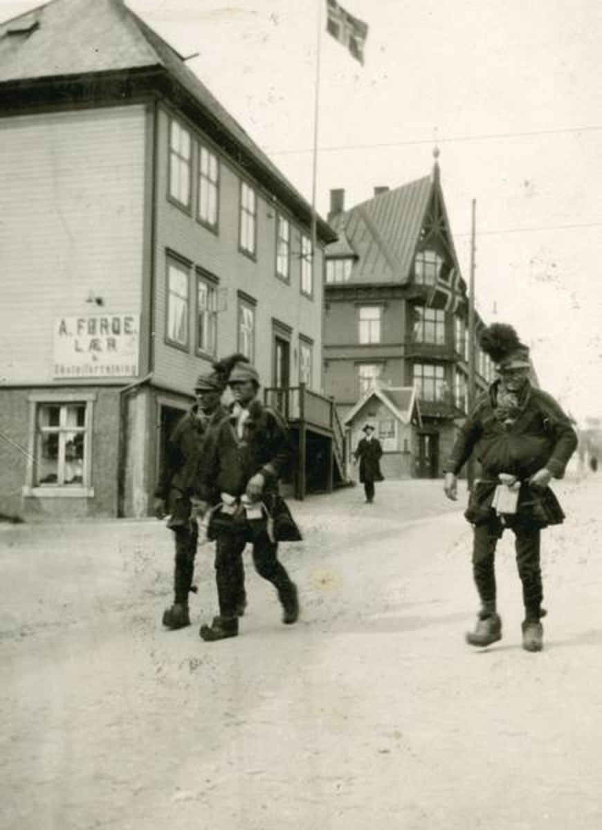 Bygate med 3 samer i samedrakt. Tusenhjemmet bak og Skarbogården nærmest. Flagg.
Brekkan-kiosken ble seinere flyttet over Skolegata til Furunesgården. Skilt: A Førde Lær.