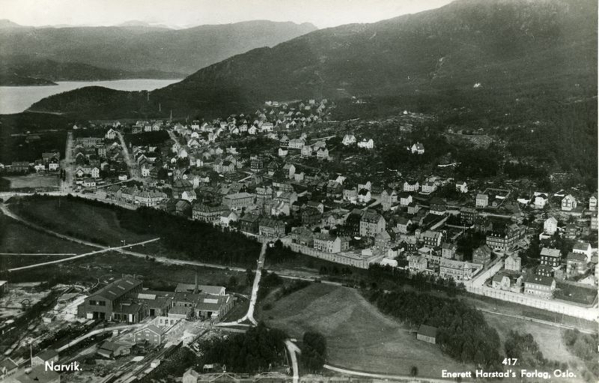 Narvik, NSB verksteder,Oscarsborg. Bildet er mest sannsynlig tatt i august 1929. Da var Karl Harstad i Narvik med fly merket N-39 og fotograferte. På dette tidspunkt var akkurat Frydenlundsbrua ferdig (åpnet 15.09 1928), Torvhallen var ennå ikke bygget (ferdig nov. 1930) og de tre husene (Arnt Hofseth, Kolflaath og Centralkafeen) på Torvet ved den gamle overgangen til Frydenlund er revet noe som skjedde i 1929.