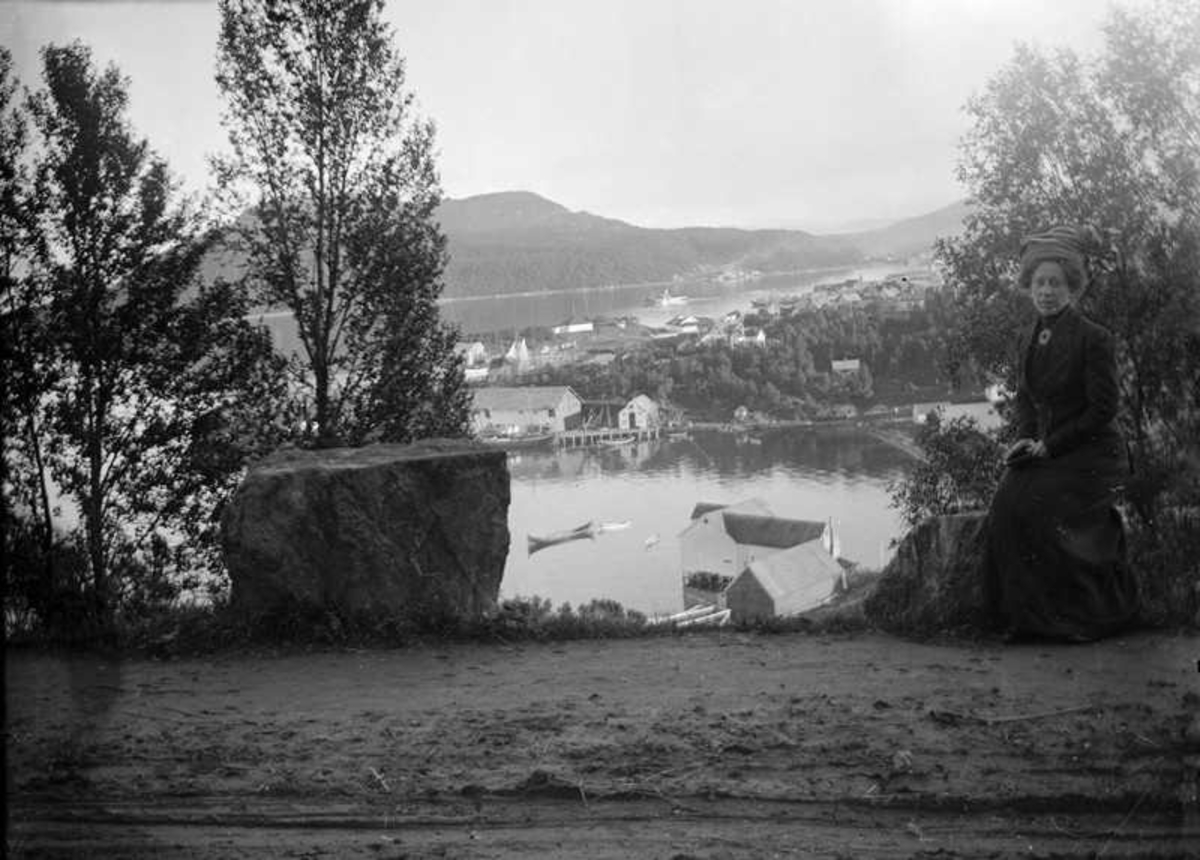 Leonarda Norman sitter ved en vei med utsikt over Samasjøen og Holstebrygga..