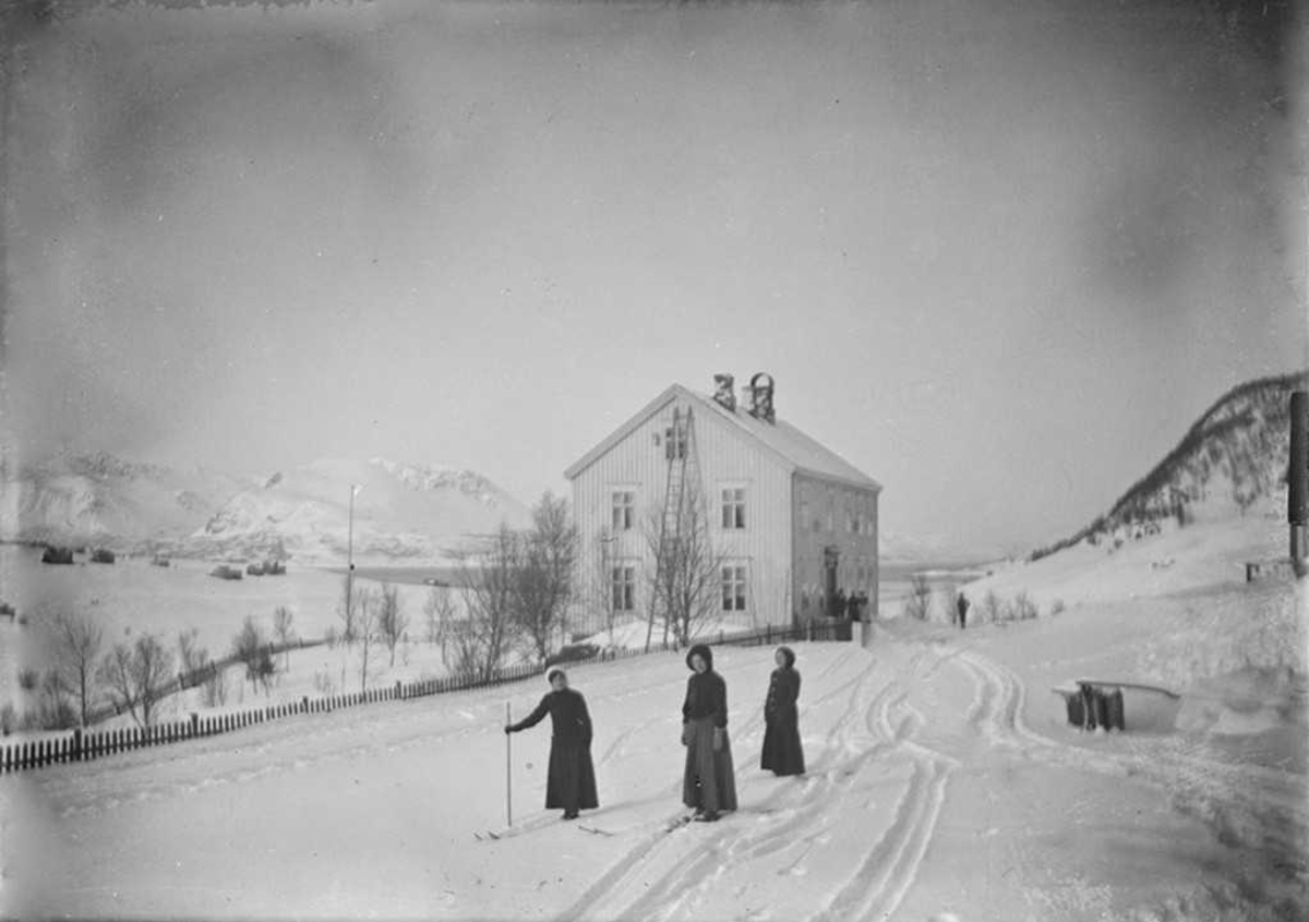 Vinterstemning. Tre kvinnelige skigåere foran et hus.