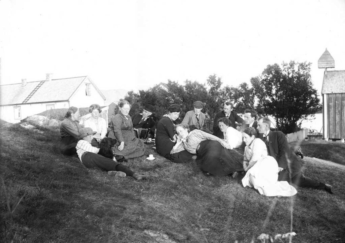 Gruppe samlet på gressbakken på Korsnes. Stabburet med klokketårnet til høyre. Vi ser Marie, Claudia og Magdalene.