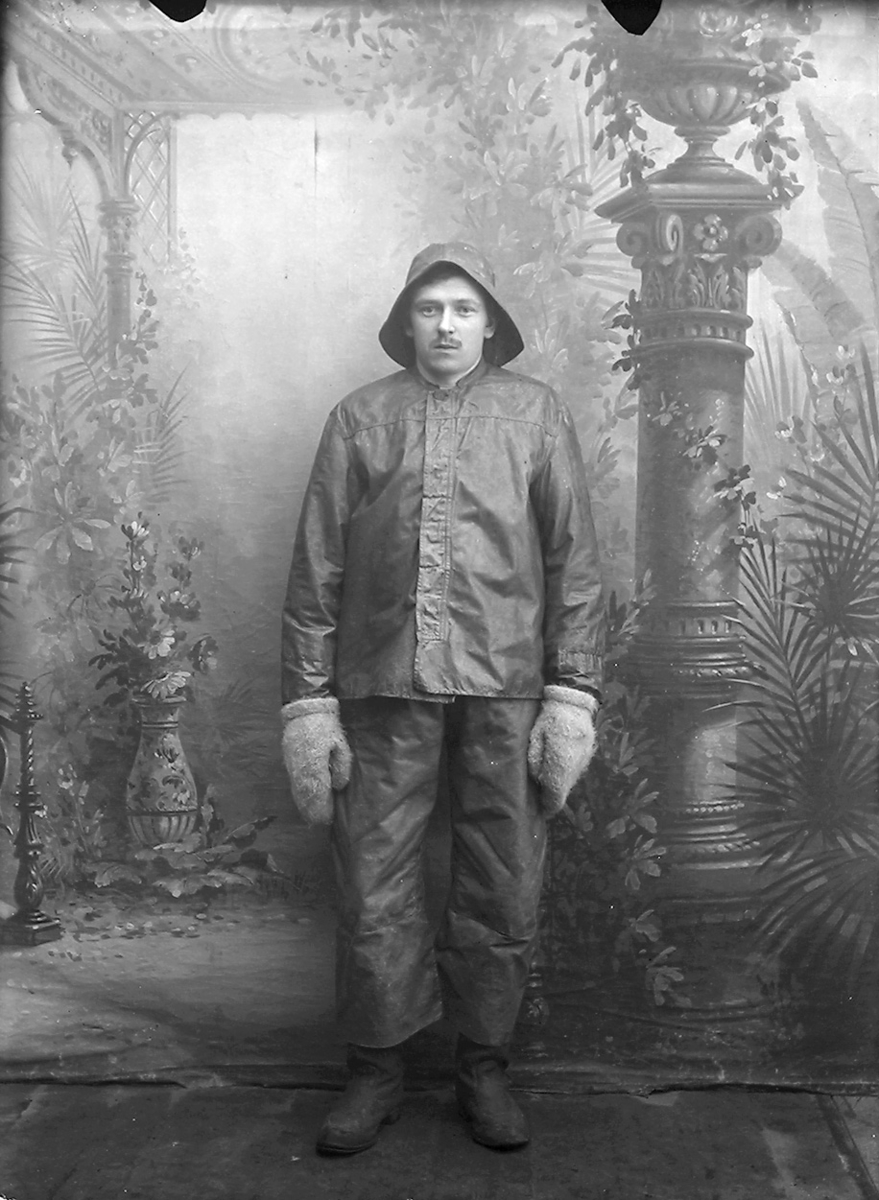 Portrett. Mann i 20-åra. Står. Sydvest. Oljehyre. Sjøvotter.Bildet er tatt på Reine i Lofoten.