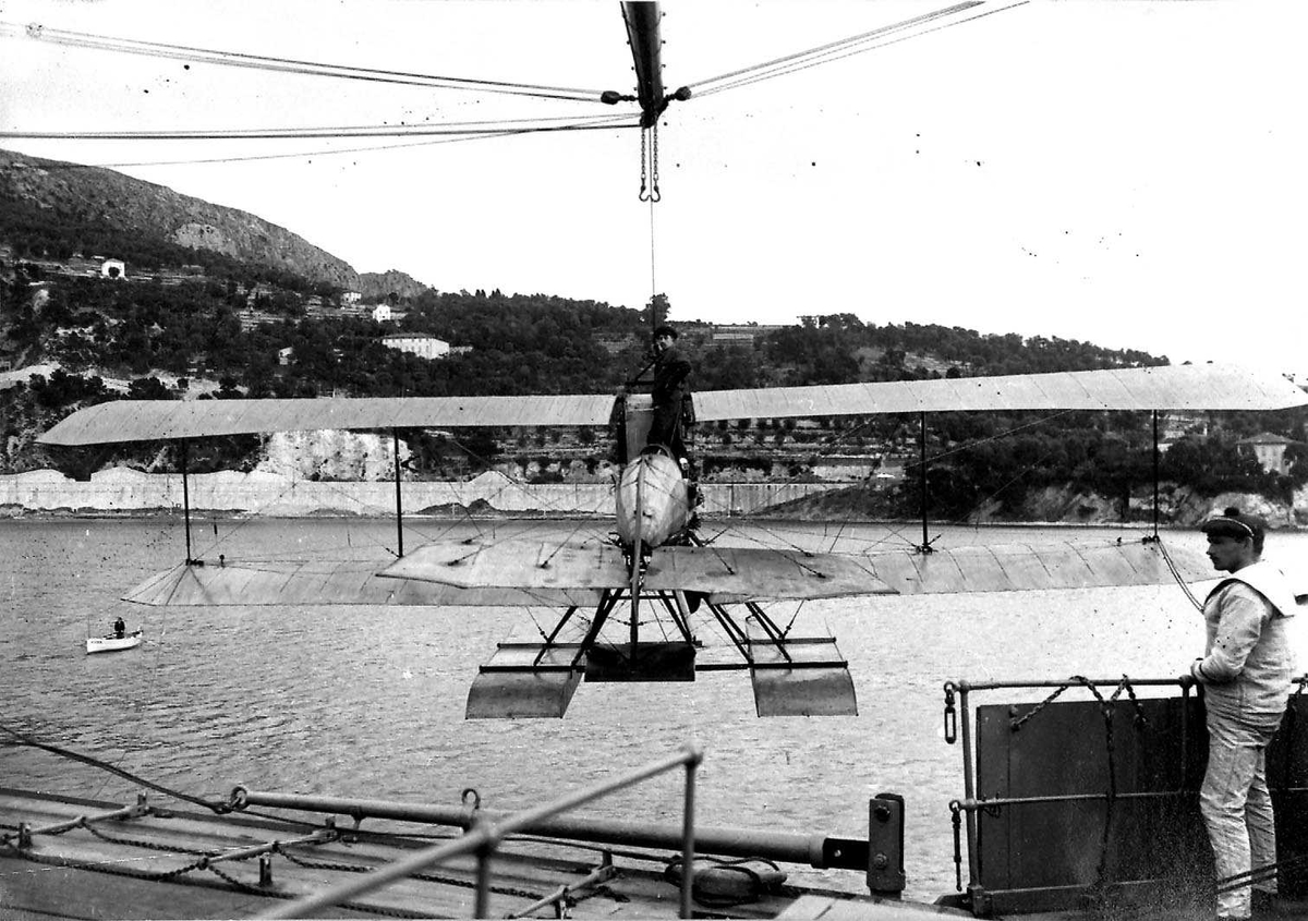 Ett fly henger i bommen på ett fartøy, Breguet H.U.2. Noen personer ved flyet.