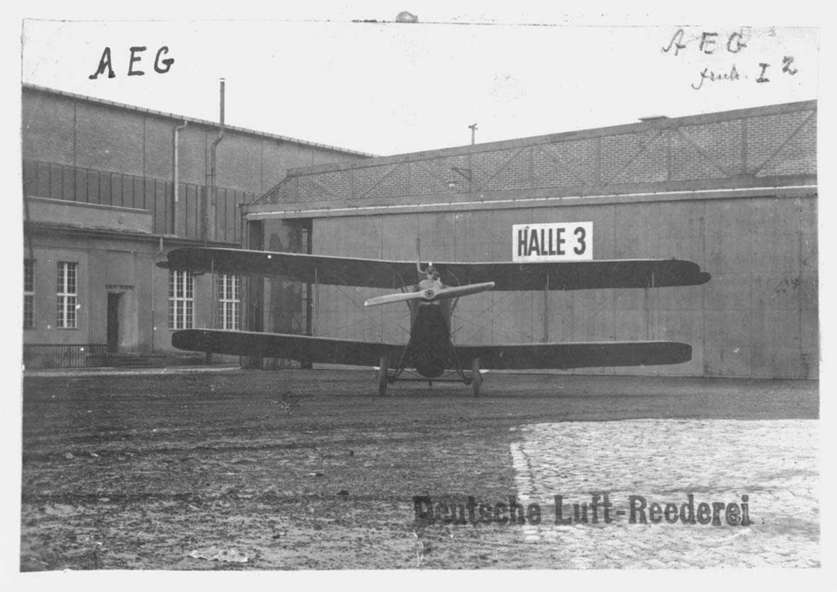 Ett fly på bakken. A.E.G. C I. Bygning/hangar i bakgrunn