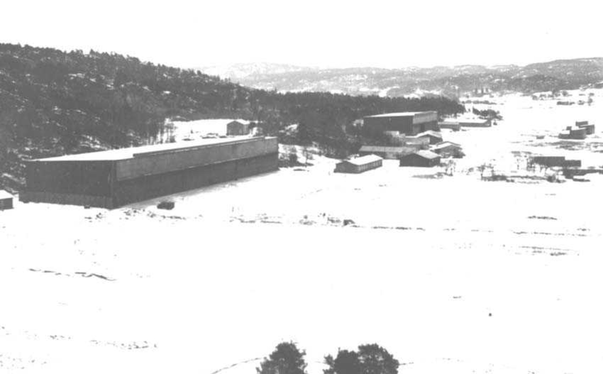 Oversikt over flere bygninger. Fjell i bakgrunnen.