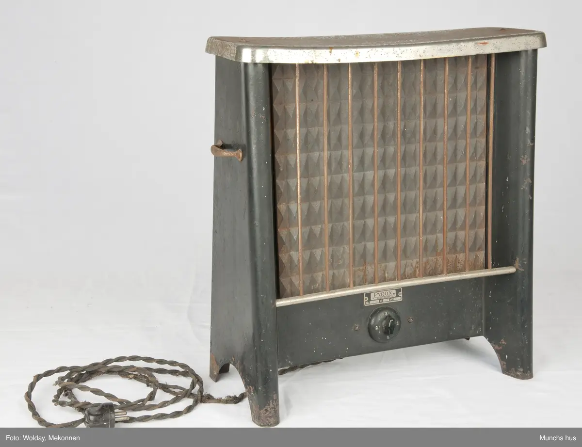 Elektrisk varmovn i stål. Merke Pyrox. 
Ovnen er meget tung, sortlakkkert med forniklet topp. Toppen er lett angrepet av rust. Den yter 900 watt - 225 Volt. Utstyrt med tretrinns bryter. 
Fronten er utstyrt med et beskyttelsesregister som består av ni tynne stenger. Et bærehåndtak på hver side.