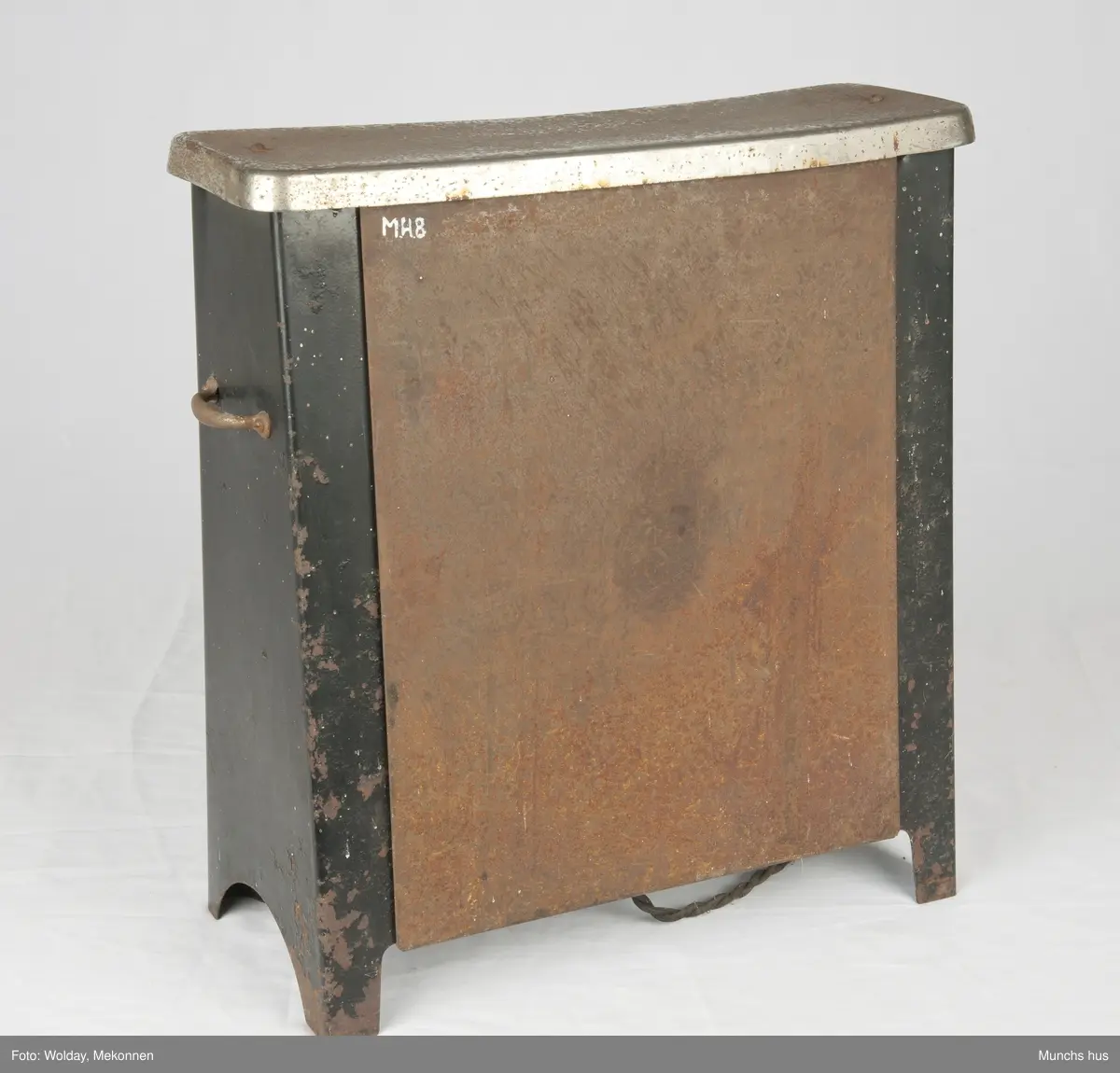 Elektrisk varmovn i stål. Merke Pyrox. 
Ovnen er meget tung, sortlakkkert med forniklet topp. Toppen er lett angrepet av rust. Den yter 900 watt - 225 Volt. Utstyrt med tretrinns bryter. 
Fronten er utstyrt med et beskyttelsesregister som består av ni tynne stenger. Et bærehåndtak på hver side.