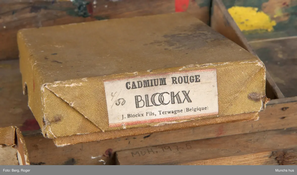 Malerskrin, hengslet i bakkant. Det er fire rom i bunn. Innhold i skrinet: 1 eske (med lokk) med påklistret lapp: CADMIUM ROUGHE BLOCKY J. Blockx Fils, Terwagne (Belgique) innholder 20 kullstiftbiter. 1 eske (mangler lokk) innholder 3 fargestifter (Grønn: TRADE MARK "CRAYOLA" BINNY & SMITH CO. NEW YORK. Brun: Faber. Grå: 169, L. F. Raffael.. Dusseldorf, samt rester av hvit farge fra en malingtube ant.
1 ti-øring fra 19(4?)9 ? 4 trebiter i ulike størrelser, en pappbit med anker som motiv, samt bokstavene L F.