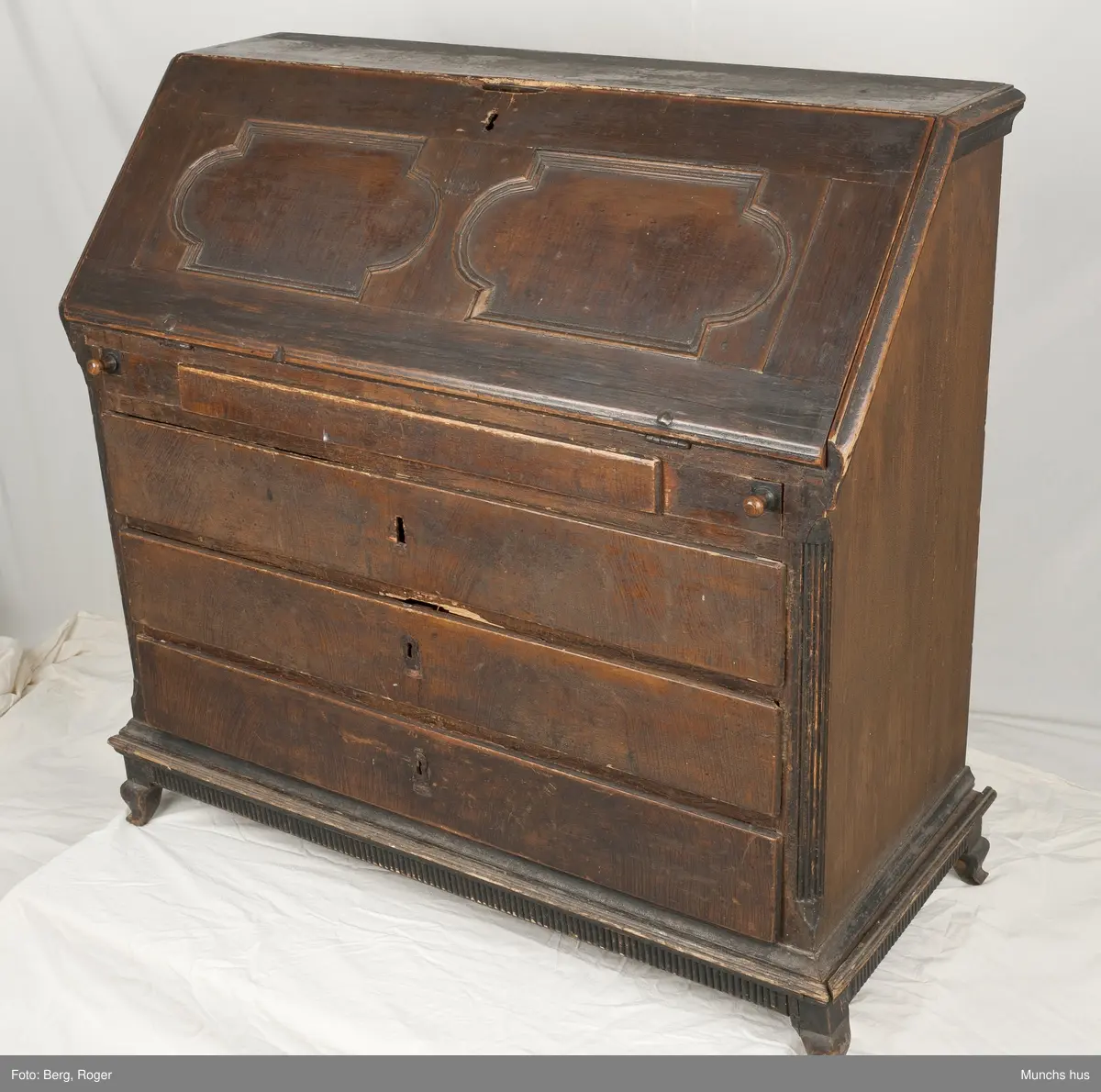 Et skatoll med 4 skuffer og sarg.  To speil i klaffen ni små skuffer inni og tre rom.