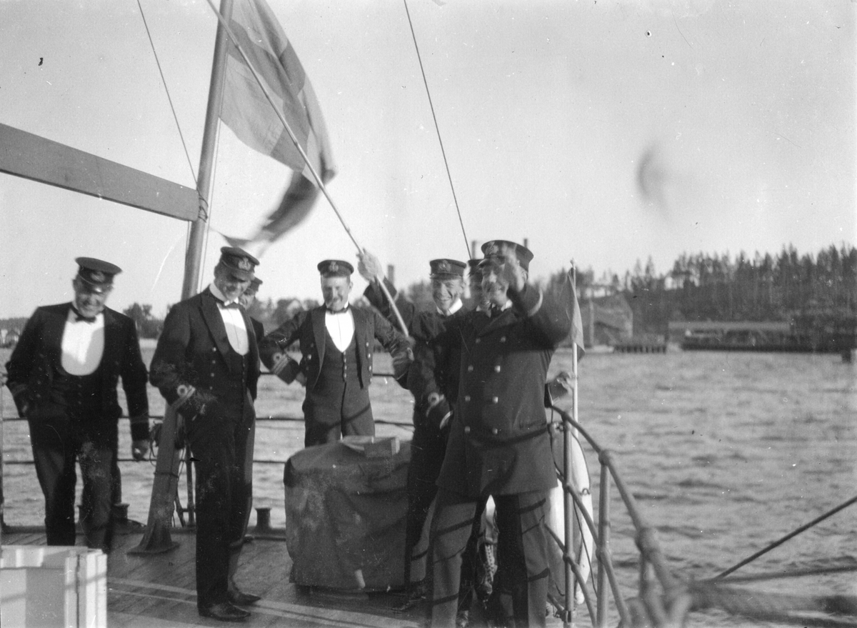 Glada herrar firar på fartygdäck iklädda uniform.
