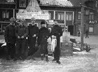 Fem män i vintermundering  i Vaxholm 1911. Bakom syns hus med texten Ytterbystrand.