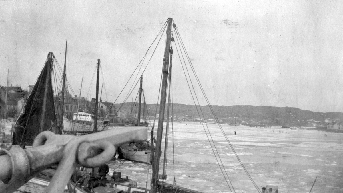 Hamnen i Marstrand 1916-1917. Segelbåtar ligger i en istäckt hamn. I förgrunden syns båtmaster.