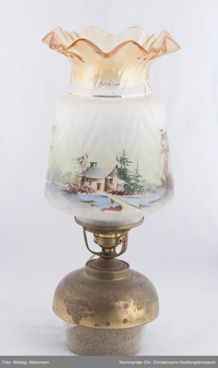 Oljelampe. Glass, blåst i form. Påmalt landskap med kirkebygning og hus. Topp er farget brunlig.