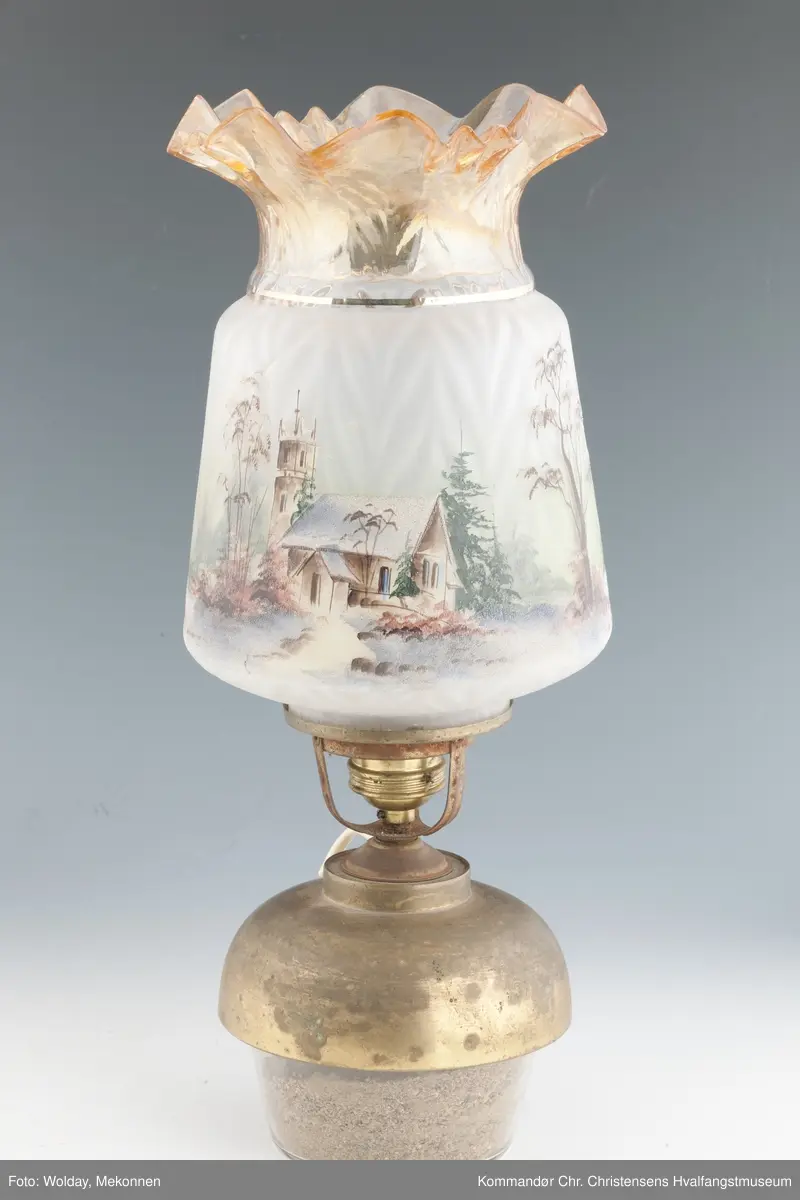 Oljelampe. Glass, blåst i form. Påmalt landskap med kirkebygning og hus. Topp er farget brunlig.