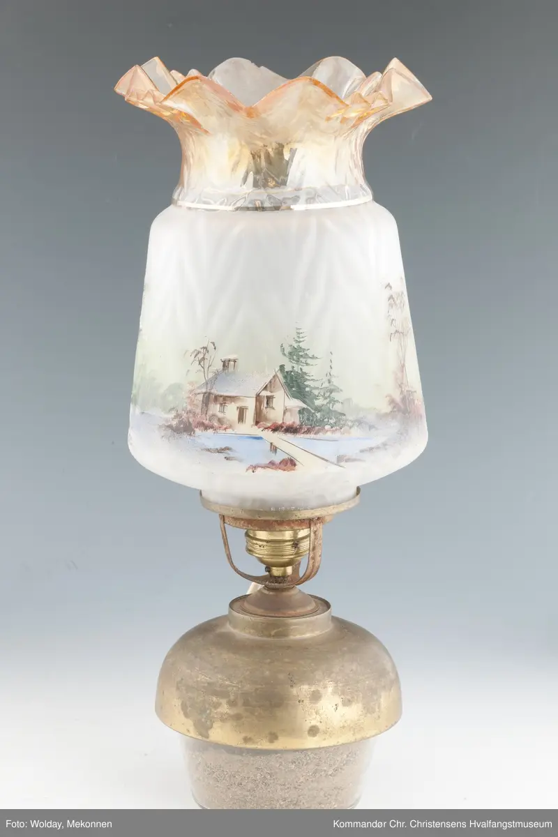 Oljelampe. Glass, blåst i form. Påmalt landskap med kirkebygning og hus. Topp er farget brunlig.