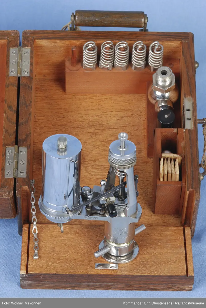 Indikatoren ligger i en trekasse m. diverse tilbehør. Indikatoren ble brukt til å måle trykket dvs. effekten av maskinen. Instrumentet tegnet diagram som kunne leses av for å beregne virkningsgrad, trykk, lekkasjer o.l