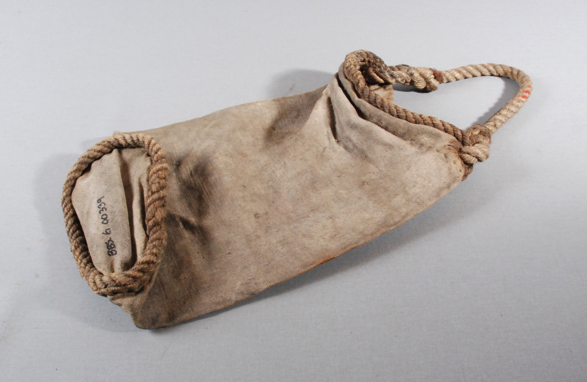 Brannbøtte i lerret, med taukant rundt øverste og nederste kanten av bøtten. Hanken er av tauverk som er tredd gjennom øverste kanten av bøtten.