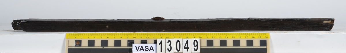 Splitter.  Svagt kilformat tvärsnitt. Båda ändarna avbrutna Ena långsidan är bortspjälkad, den andra är fasad. En av ytorna visar spår efter att ha blivit bearbetad av yxa eller (troligare) skavjärn. Den andra sidans yta uppvisar karaktäristiska spår efter skavjärn.

Möjligen är detta en del av en laggstav till en tunna. Dimensionerna, de stående årsringarna samt fyndkontexten talar för detta.