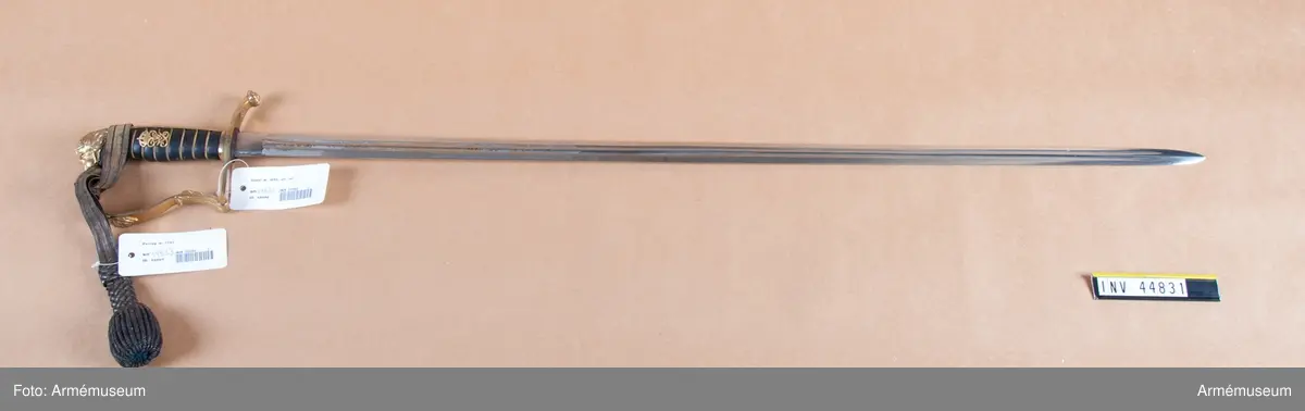 Klingan tillverkad hos E. Svalling, Eskilstuna. Kaveln pryds på bägge sidor med Gustaf V:s namnchiffer. Sabeln lika med AM 39928 (äldre nr 5250) med undantag att baljan är brungjord.