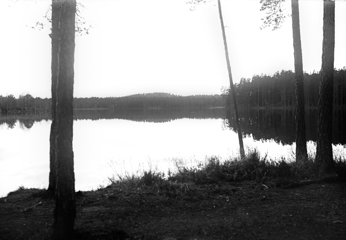 Sjön ligger spegelblank med skog runt omkring.