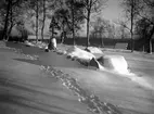 Fotspår syns i snön utmed stengärdesgården. i Den trädbevuxna backen ligger några hus.