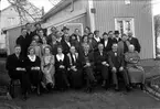 Selma (i mitten av främre raden) firar sin 60-årsdag i början av mars 1934 och firas av släkt och vänner. Bilden är tagen utanför huset på Åsenvägen 71 i Mariebo 10, Jönköping. På en skylt på husgaveln står 