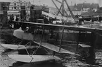 Flygplan Farman HF 23 - SW 11 startar från hamn. I passagerarsits Prins Wilhelm. I bakgrunden står åskådare på ett fartyg.