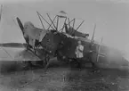 Militärer och flygare framför flygplan AEG G.V vid landning utanför Kristianstad under leveransflygning år 1919. Flygplanet var på väg till Flygkompaniet på Malmen.