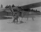 Flygplan Albatros BIIa med skidor framför tälthangarer i Boden, vintertid, 1916. En man står vid propellern.