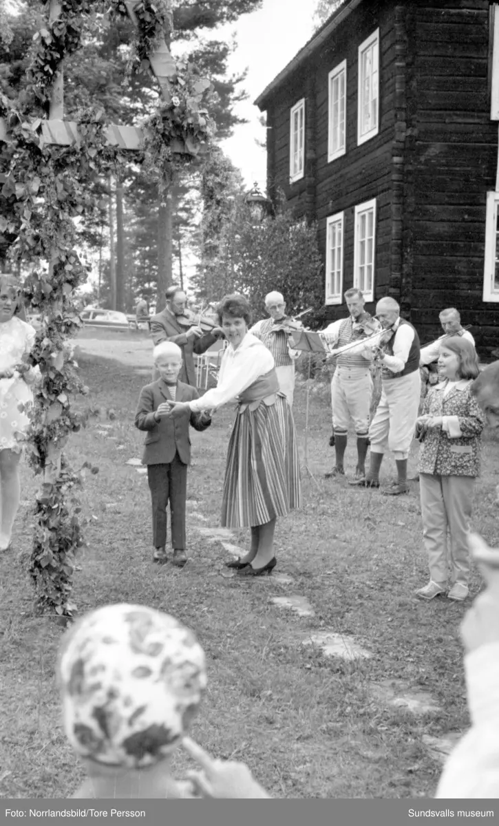 Midsommarfirande på Huberget i Stöde, med spelmän och dans kring midsommarstången.