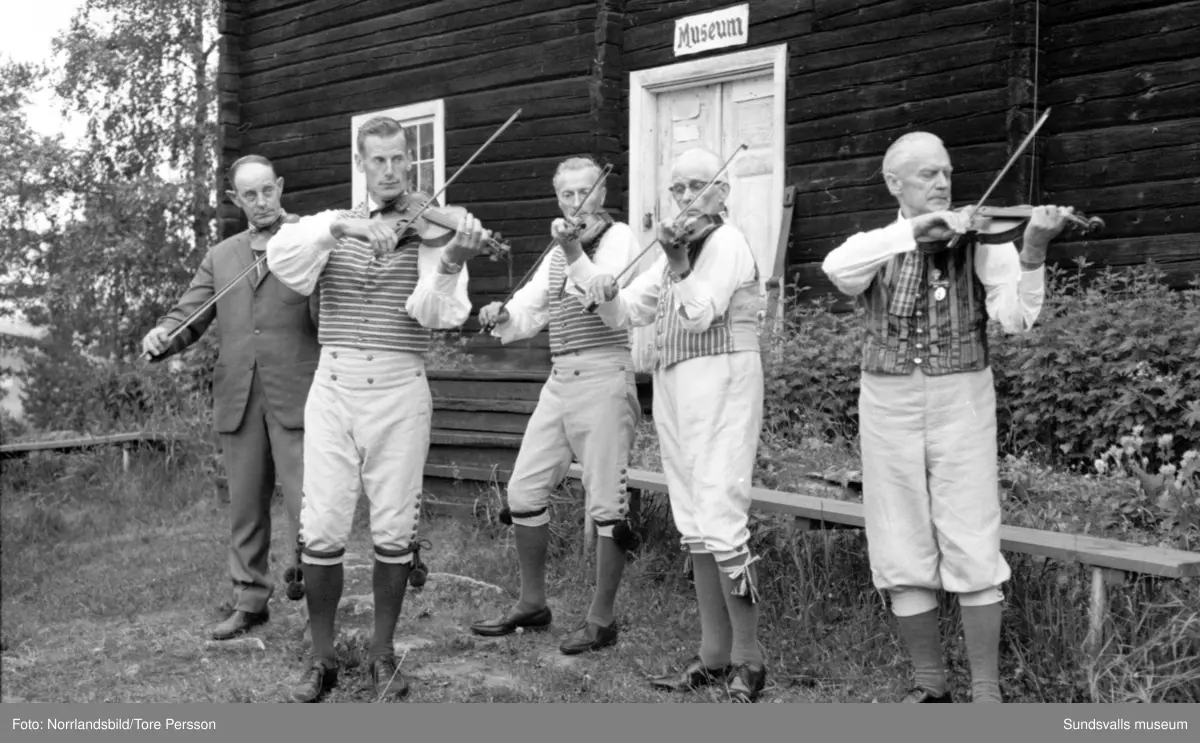 Midsommarfirande på Huberget i Stöde, med spelmän och dans kring midsommarstången.