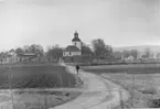 Istorp. Kyrkan på håll. Liten väg som slingrar sig genom landskapet.