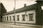 Emil Berggrens hus vid Kronogatan 7 i Vänersborg, fasad mot gatan. Från höger de två fönstren till förmaket med gaslyktan emellan, så de tre salsfönstren med reflexionsspegeln vid det första, därefter tamburfönstret och så två fönster till den dublett, som brukade hyras ut.